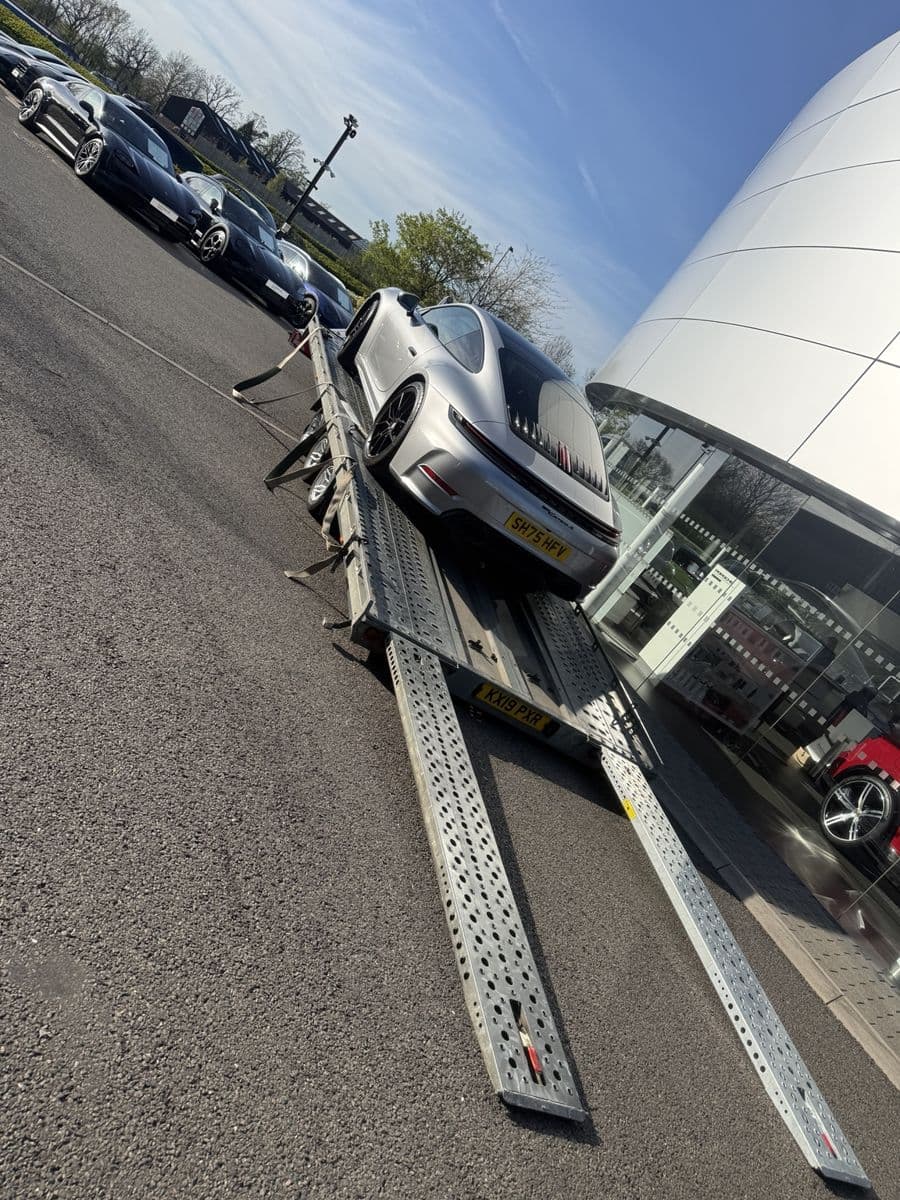 Silver Porsche secured to a vehicle transport trailer